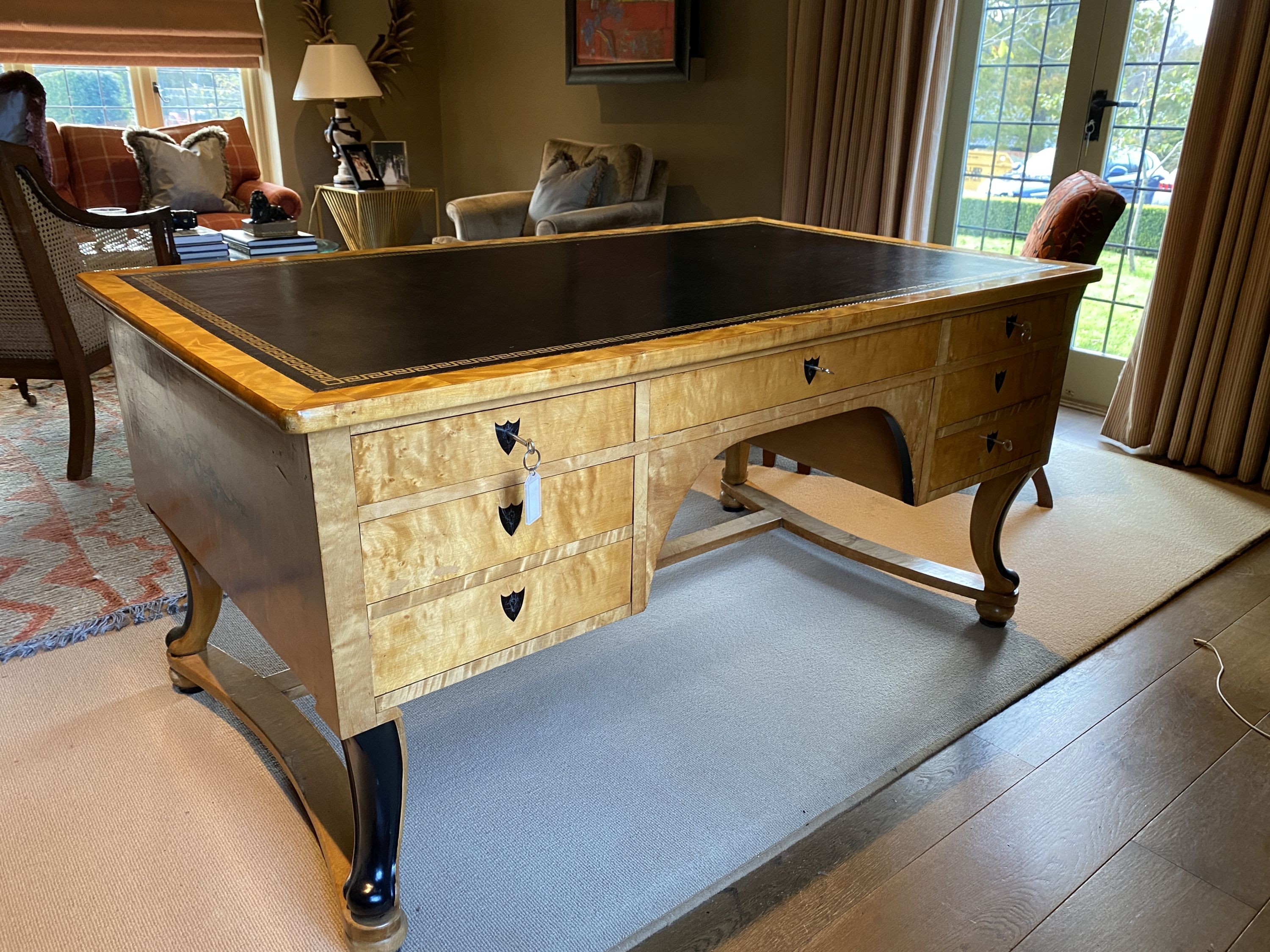 A Biedermeier style maple desk, with black leather skiver and seven drawers, on ebonised scroll legs with H stretcher, width 155cm depth 91cm height 76cm